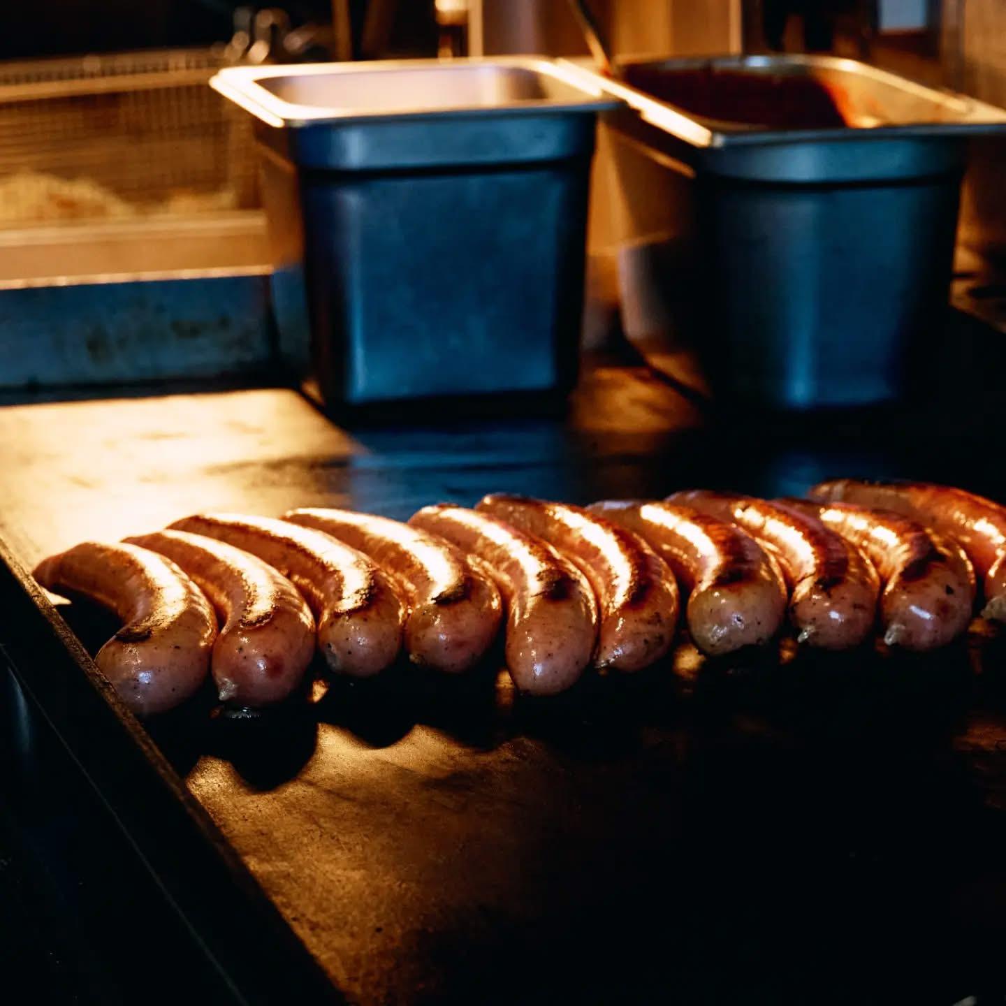 Bratwurst sizzling on The Currywurst's flat-top grill