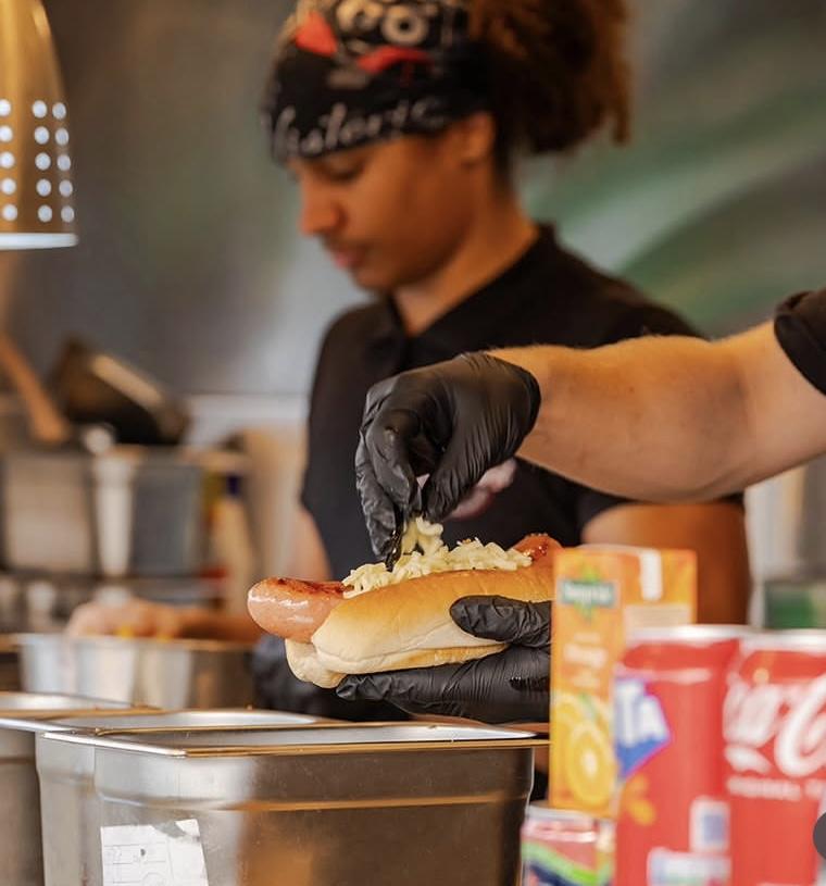 Cheese being added to a hot dog